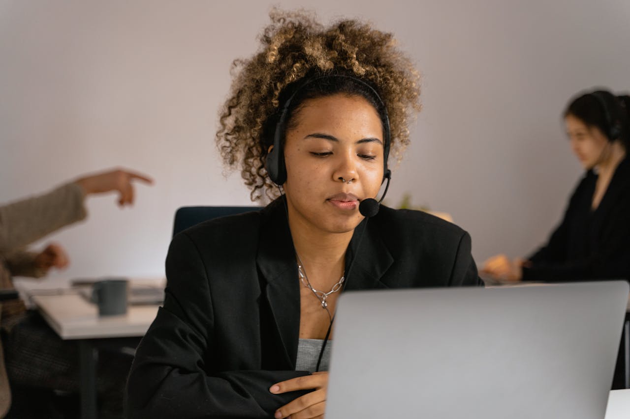 African American woman working in a call center with headphones on.